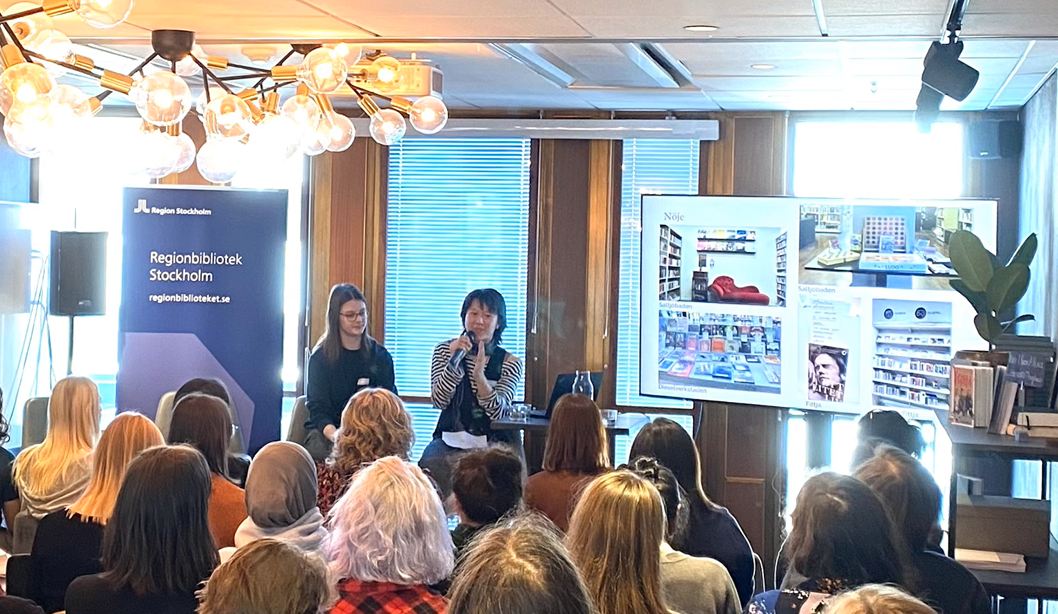 Två personer på scen. Publik i förgrunden.