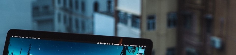 Datorskärm med stadsvy i bakgrunden. Från Unsplash.